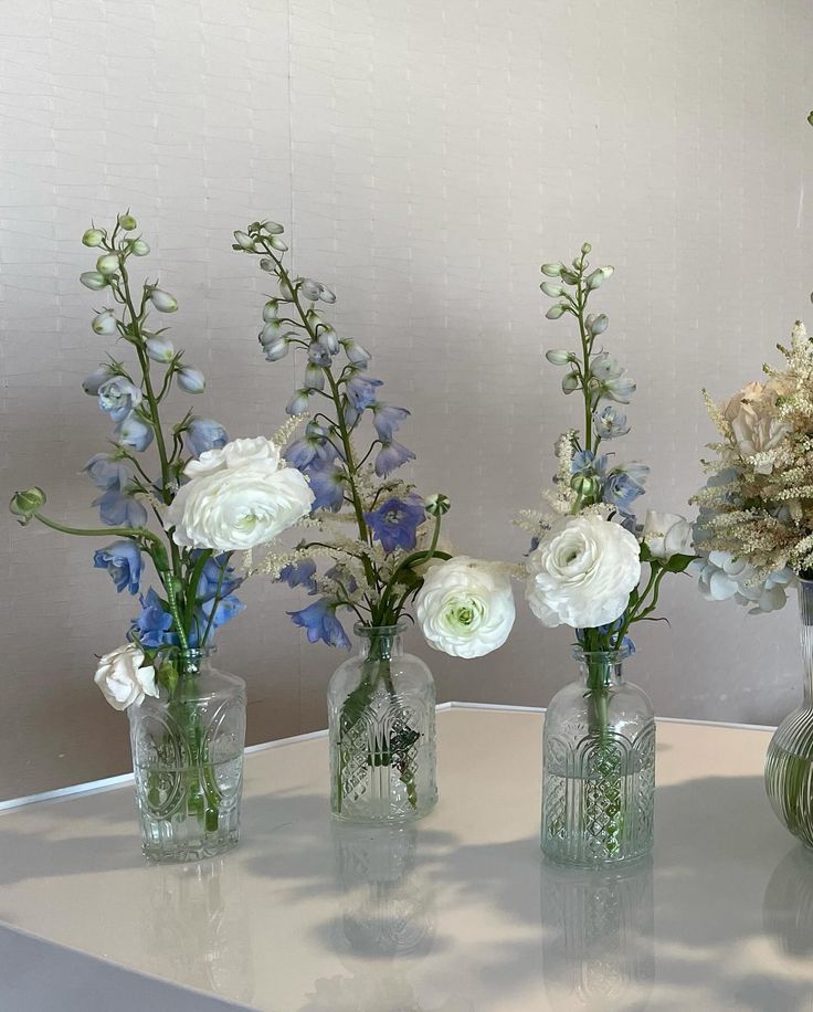 four glass vases with flowers in them on a table