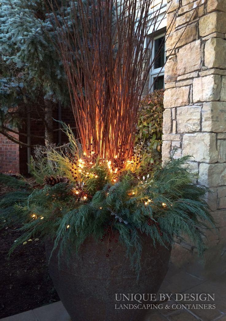 a planter with lights in it sitting next to a brick wall and stone building