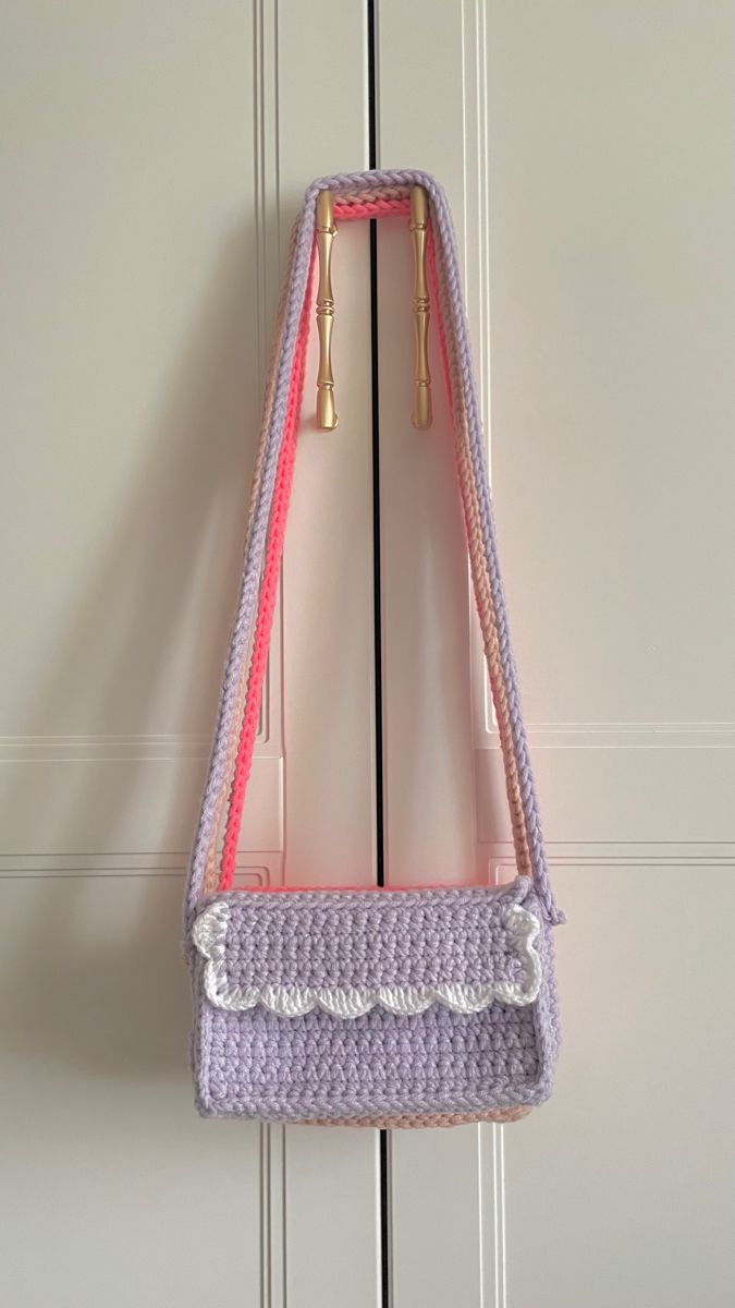 a crocheted purse hanging on a door handle with two hooks attached to it