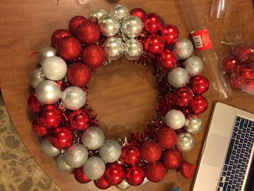 a christmas wreath sitting on top of a wooden table next to a laptop and other decorations