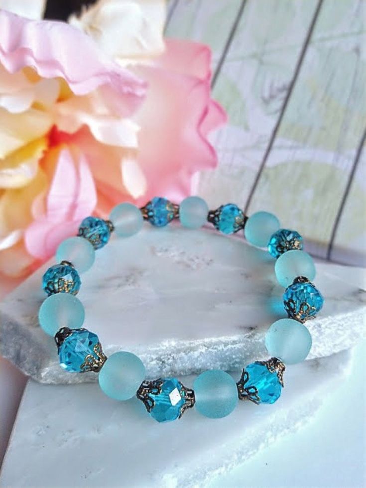 "Delicate and versatile, this classy bracelet is so feminine and a truly versatile accessory, complimenting every look while adding a little boho chic.  Product overview: - Made with 10mm frosted light blue cultured Sea Glass beads, faceted 10mm rondelle-shaped Glass Beads, and decorative Brass bead caps - Strung on a high quality stretch cord that will retain the original shape and size - Choose your length at checkout ----------------------------------------------------------- MAKE THIS A 3 PI Elegant Turquoise Bracelets For Beach, Bohemian Round Stretch Bracelet For Beach, Bohemian Stretch Bracelet For Beach, Bohemian Hypoallergenic Beaded Bracelets, Handmade Elegant Beach Bracelets, Turquoise Bohemian Crystal Bracelet, Elegant Turquoise Stretch Bracelet As A Gift, Elegant Turquoise Stretch Bracelet As Gift, Bohemian Hypoallergenic Bracelets