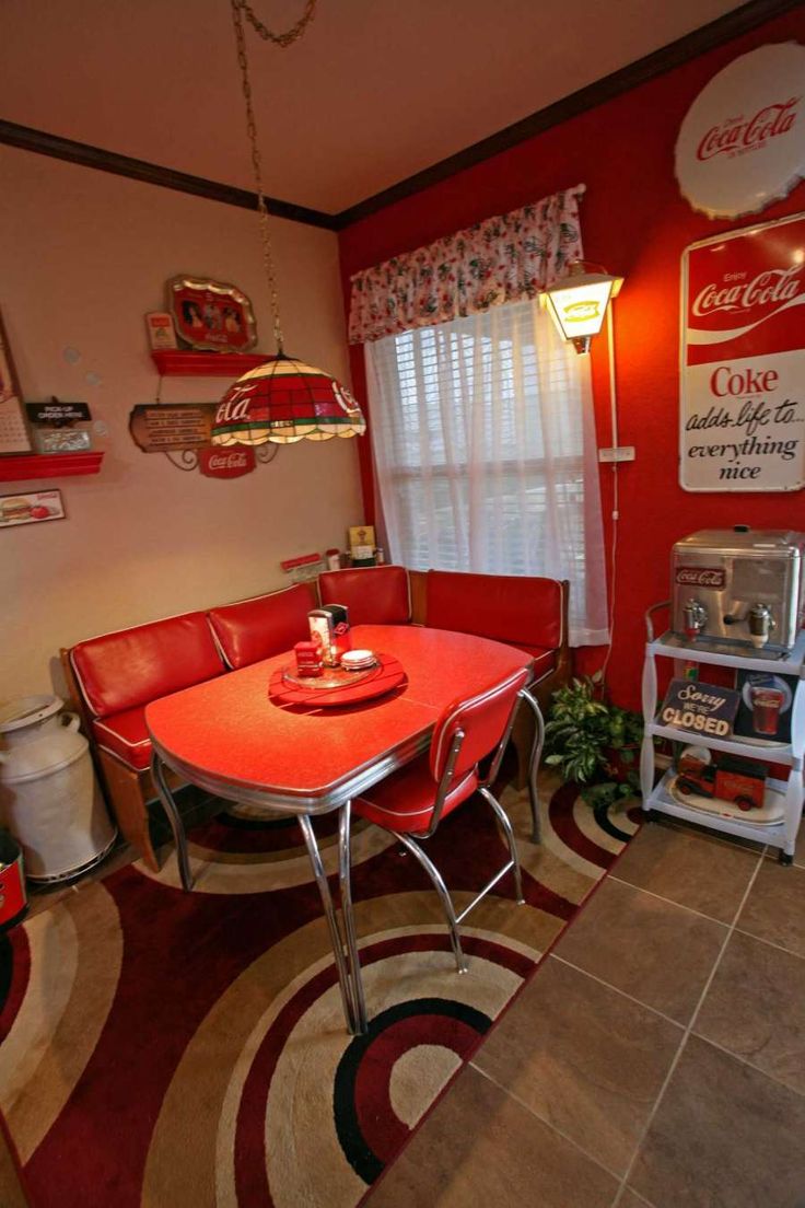 a red table and chairs in a room with coca - cola signs on the wall