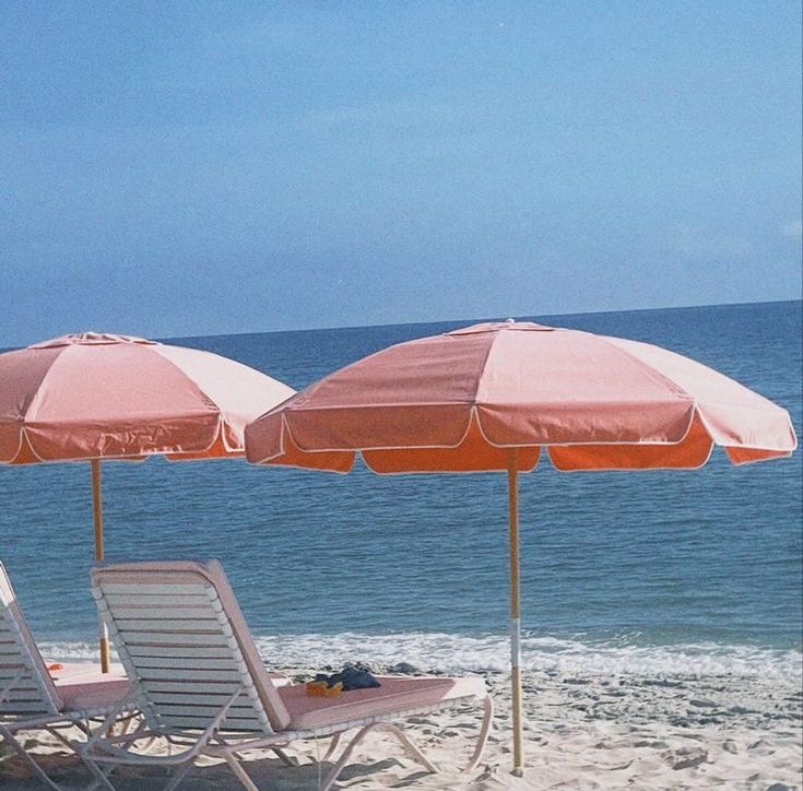 two lawn chairs and an umbrella on the beach