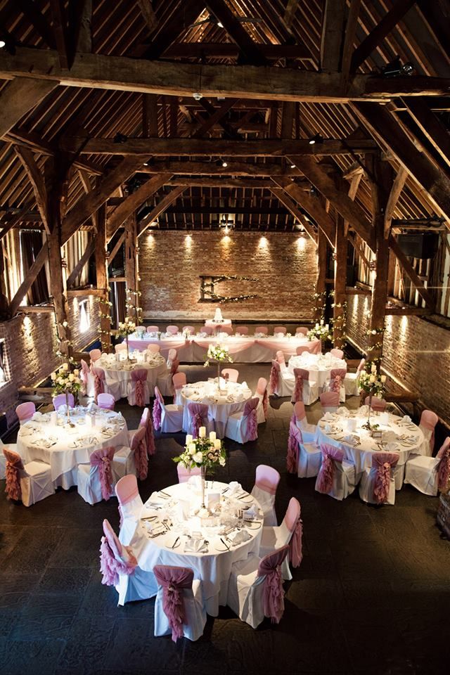 a banquet hall with tables and chairs covered in white linens, pink sashers and flowers