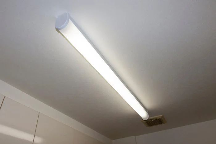 a light that is on the ceiling in a room with white walls and cupboards