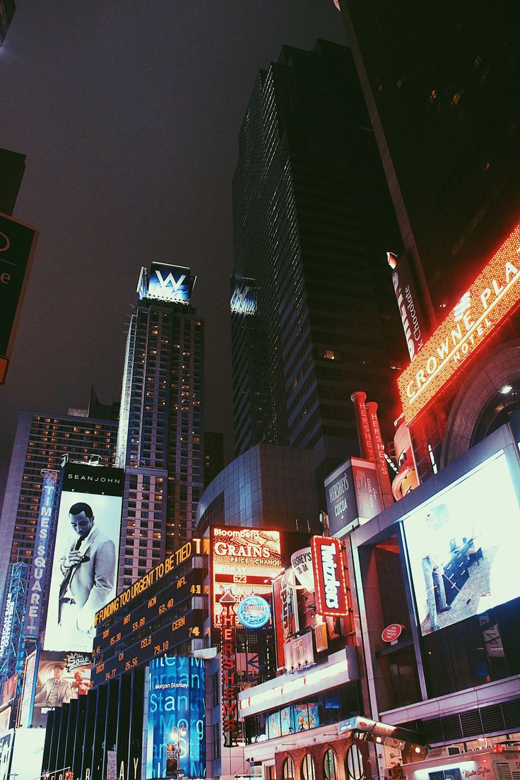 a city street filled with lots of tall buildings and neon signs at night, all lit up