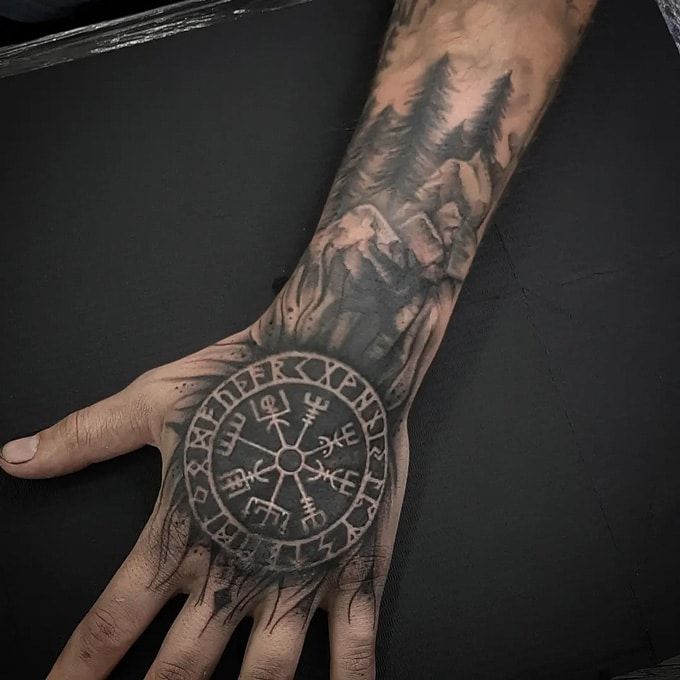 a man's hand with a compass tattoo on it