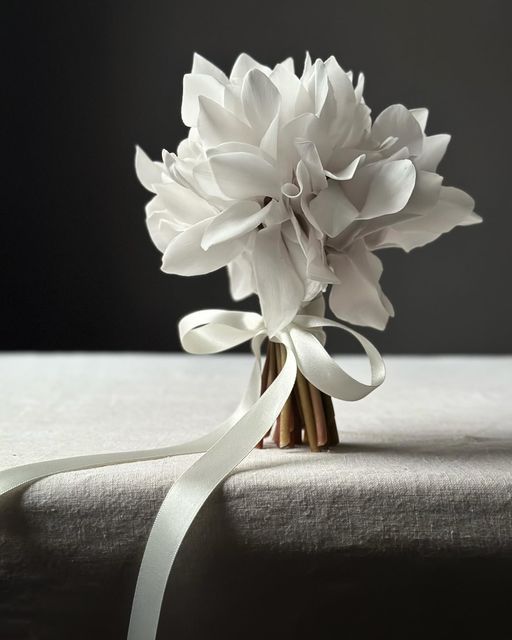 a bouquet of white flowers sitting on top of a bed next to a satin ribbon