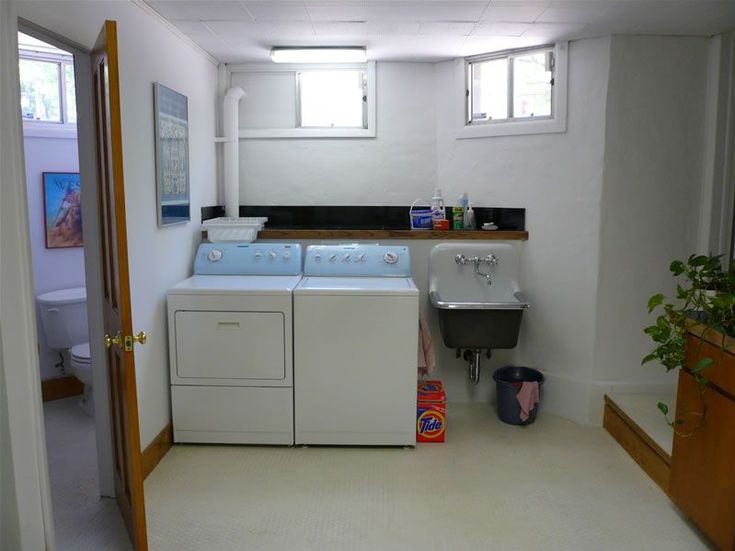 a washer and dryer sitting in a small room next to a sink with a potted plant on the counter