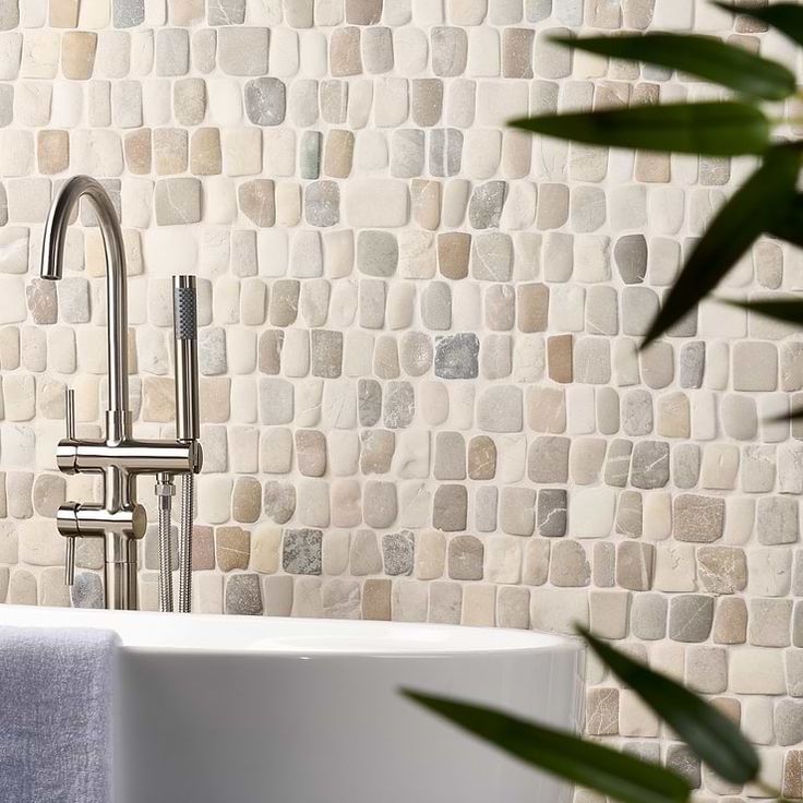 a white sink sitting under a faucet next to a wall covered in rocks