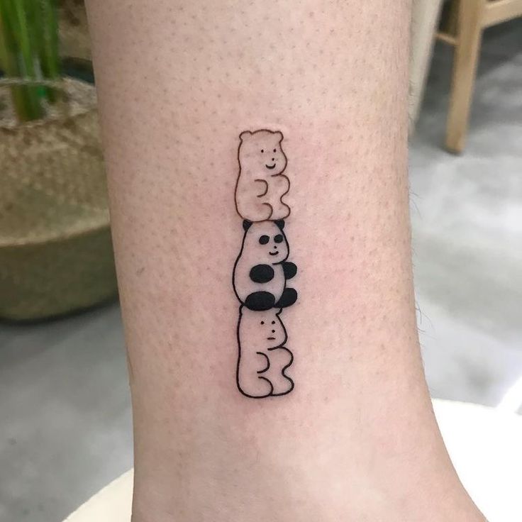 a small black and white panda bear tattoo on the ankle