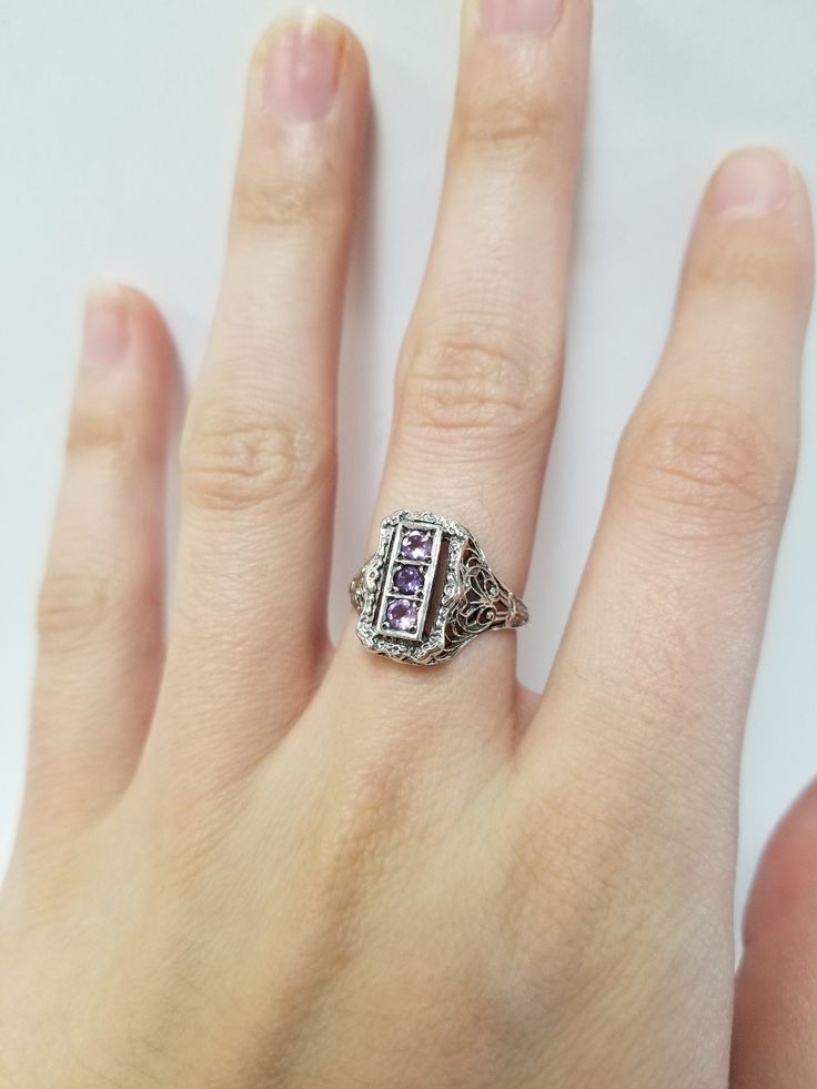 Once in a Blue Moon beautiful vintage finds. Amethyst Filigree Ring // Solid 925 Sterling Silver. Antique Remake. There are three 0.08 ct stones in a beautiful filigree setting. Beautiful anniversary present, Mother's Ring, or Birthday gift. Size: 6, 7, 8 US* Total Carat Wt: 0.24 ct Band width: 1.6 mm *Ring sizes may be 1/4 smaller than size selected Free Shipping & packaged in a black velvet ring box ready to gift! Fine Jewelry With Accent Stones For Collectors, Vintage Emerald Cut Birthstone Rings, Antique Sterling Silver Jewelry With Birthstone, Antique Sterling Silver Birthstone Jewelry, Vintage Amethyst Ring With Accent Stones For Anniversary, Vintage Amethyst Crystal Ring With Gemstone Detail, Vintage Amethyst Crystal Ring With Gemstone, Victorian Birthstone Promise Ring Jewelry, Vintage Purple Sapphire Gemstone Ring