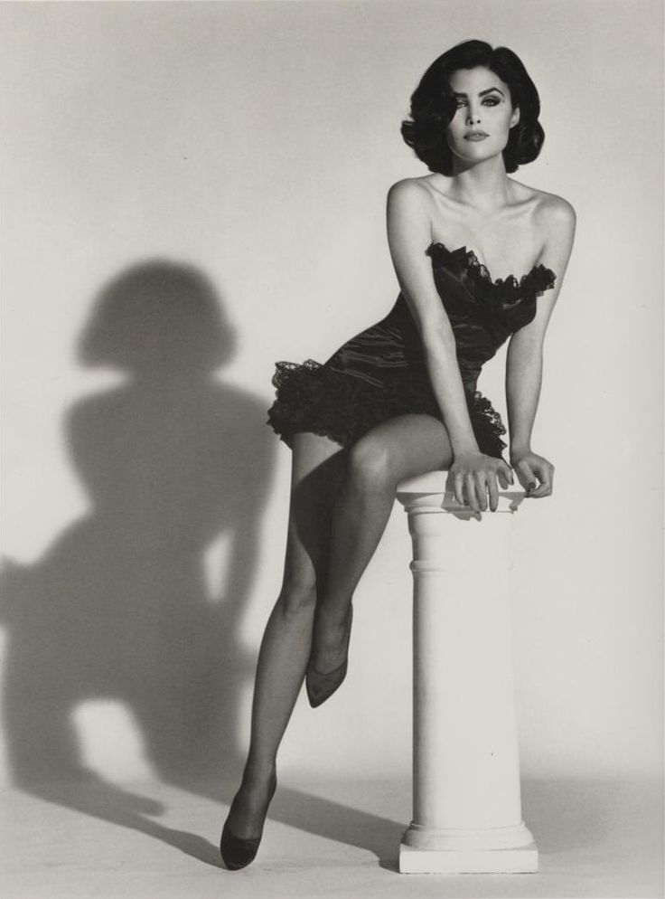 a black and white photo of a woman sitting on a pillar