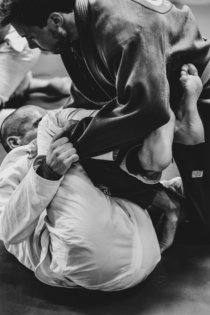 a man in black and white is doing a trick on another man's back