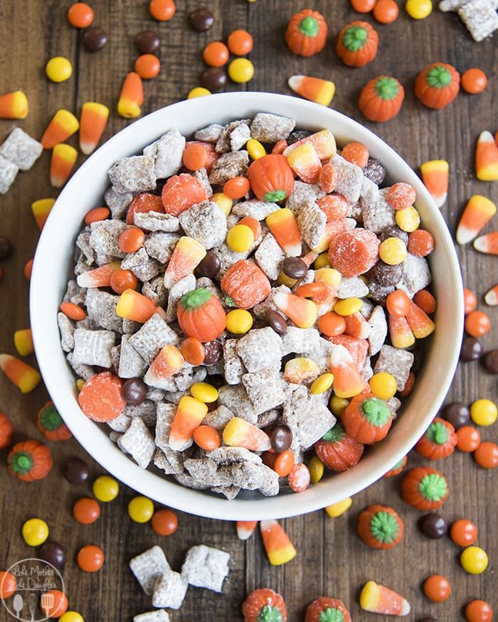 a white bowl filled with candy corn and candies on top of a wooden table