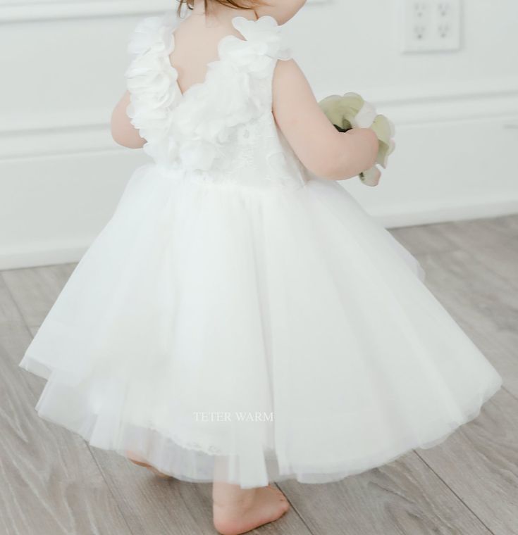 The Amelia Christening Dress by Teter Warm Couture is a beautifully designed piece that embodies purity and grace for a christening ceremony. It features a classic round neck and a sleeveless lace bodice that adds a touch of delicate sophistication. The back zip closure provides a secure and smooth fit, ensuring comfort throughout the event. The dress is finished with a layered tulle skirt that creates a soft and voluminous silhouette, perfect for the occasion. Every detail of the Amelia Dress r Baby Christening Outfit, Girls Communion Dresses, Girls Crown, Layered Tulle Skirt, Girls Pageant Dresses, Flower Girl Crown, Amelia Dress, Christening Outfit, Christening Dress