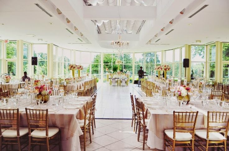 a room filled with lots of tables covered in white tablecloths and chairs next to tall windows