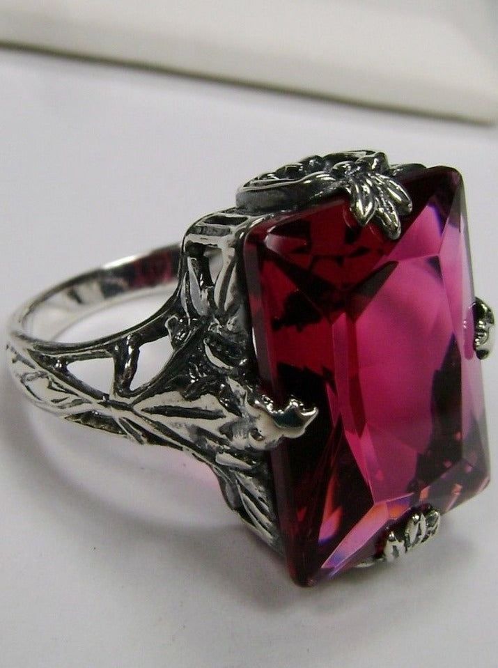 Simulated Ruby Ring Art Deco JewelryGL Design#D15 The GL design D15 is a magnificent reproduction of a classic 1930s design in sterling silver. With beautiful attention to detail, this exquisite ring features an approx. 10ct simulated/man-made ruby gemstone that lights up your outfit with dazzling color and brilliance. Set gracefully with intricate leaf filigree prongs, the stone is held securely in place, and the inside of the band is hallmarked 925 for sterling silver. The exceptional 16mm (5/ Vintage Art Deco Engagement Ring, Leaf Filigree, Star Garnet, Floral Filigree, Filigree Jewelry, Ring Art Deco, Deco Engagement Ring, Red Band, Art Deco Engagement Ring