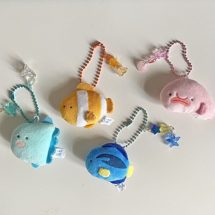 four stuffed animal key chains on a white surface