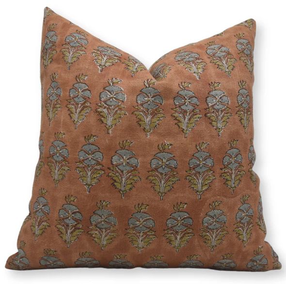 a brown pillow with blue and green flowers on it