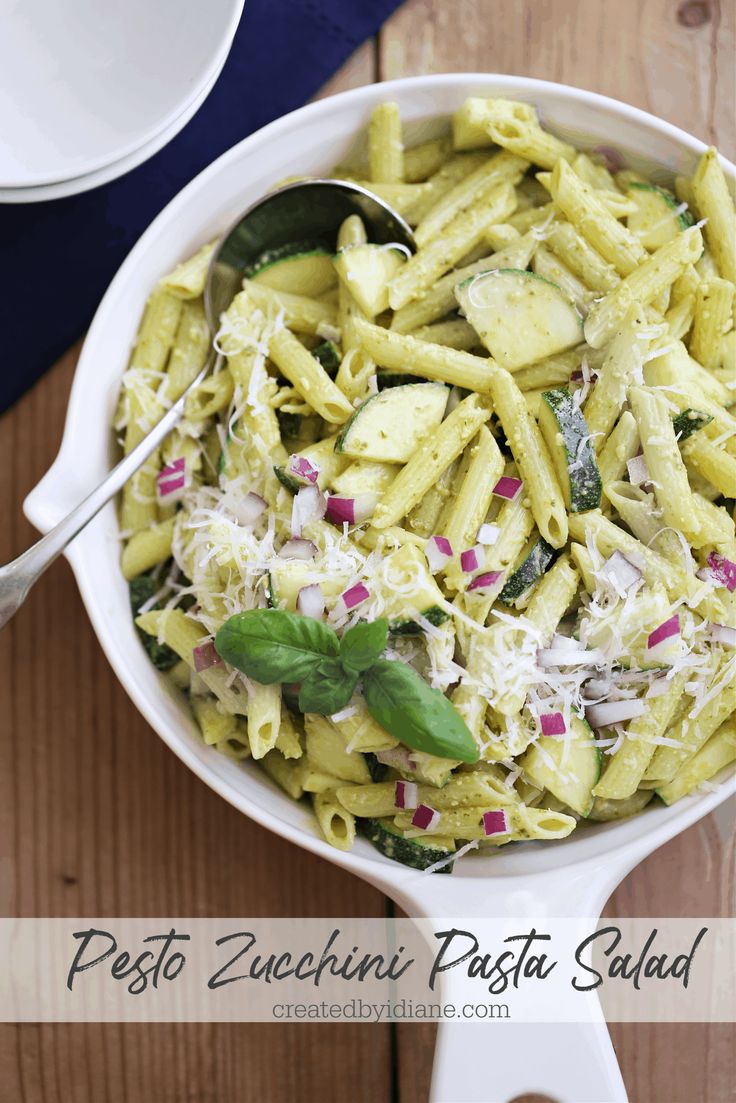 pasta with pesto and parmesan cheese in a white bowl on a wooden table