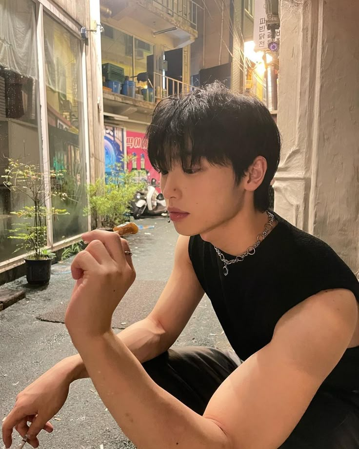 a young man sitting on the ground eating food