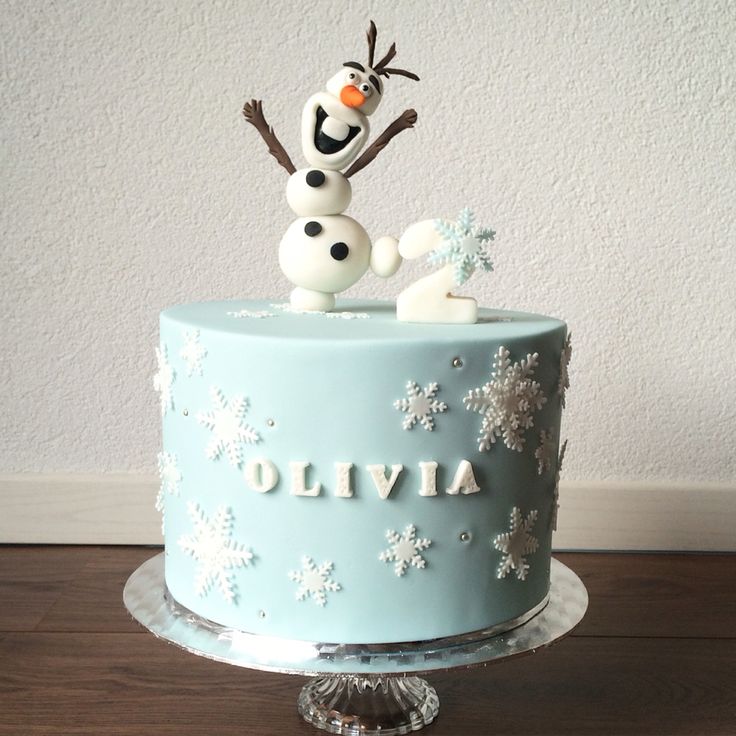 there is a frosted cake decorated with snowflakes and a frozen queen figure on top