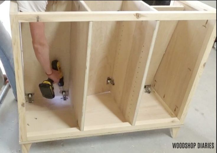 a person using a power drill to attach cabinets