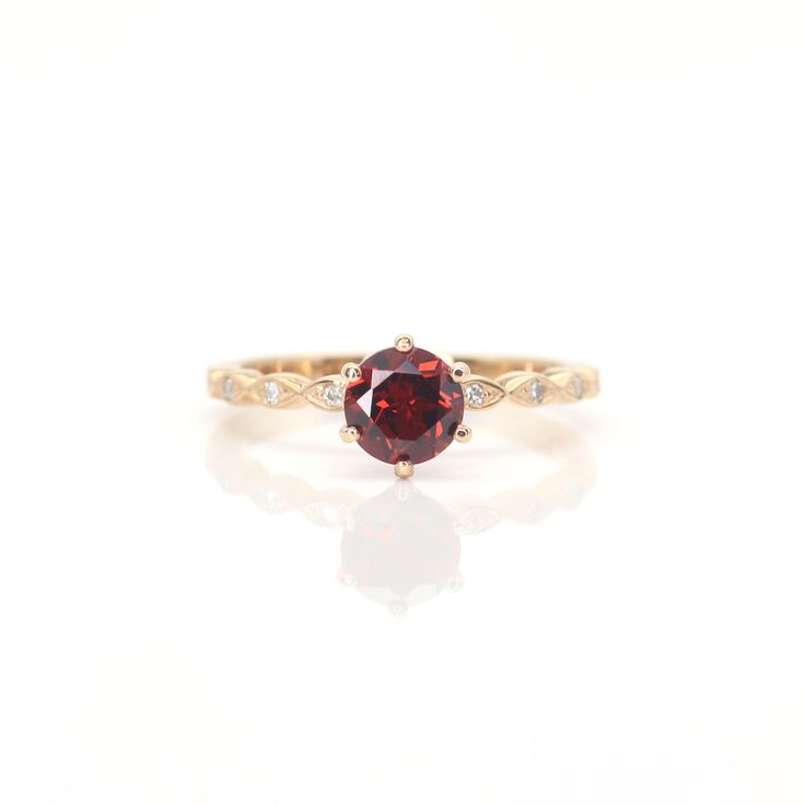 a red and white diamond ring sitting on top of a white surface with the reflection of it