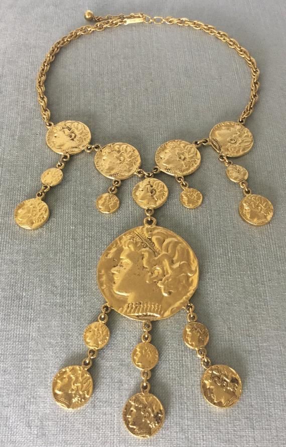 You are looking at a truly spectacular and exquisite VINTAGE TRIFARI Gold-tone Metal ROMAN COIN PENDANT CHARM BIB NECKLACE that features different sizes of coins depicting the profile of a Roman Emperor to create a massive bib that is 6” in total length, in a Baroque design with an Art Deco inspiration, SIGNED, Circa 1970's.MASSIVE AND SUPER RARE STATEMENT PIECE IN MINT AND FLAWLESS, NEVER USED VINTAGE CONDITION!!!!INCREDIBLY ELEGANT AND TRULY SPECTACULAR!!!! A TRUE WORK OF ART!!!!This superb ne Vintage Metal Coin Pendant Necklace, Vintage Metal Necklace With Coin Pendant, Vintage Coin Necklaces For Festival, Vintage Metal Coin Necklace, Vintage Coin Necklaces For Formal Occasions, Vintage Coin Necklace For Formal Occasions, Vintage Necklace With Coin Pendant, Vintage Coin Necklaces, Vintage Brass Coin Necklace