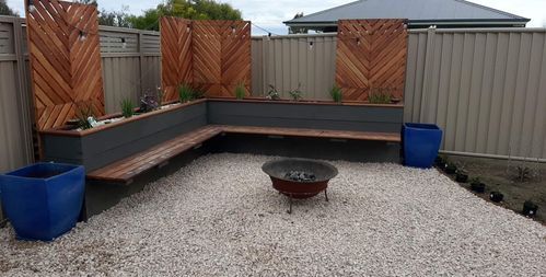 an outdoor seating area with gravel and wooden privacy screens on the fenced back yard