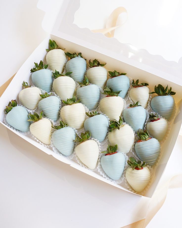 a box filled with blue and white chocolate covered strawberries