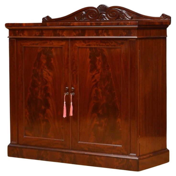 a wooden armoire with two doors and an ornate design on the front, along with pink tassels