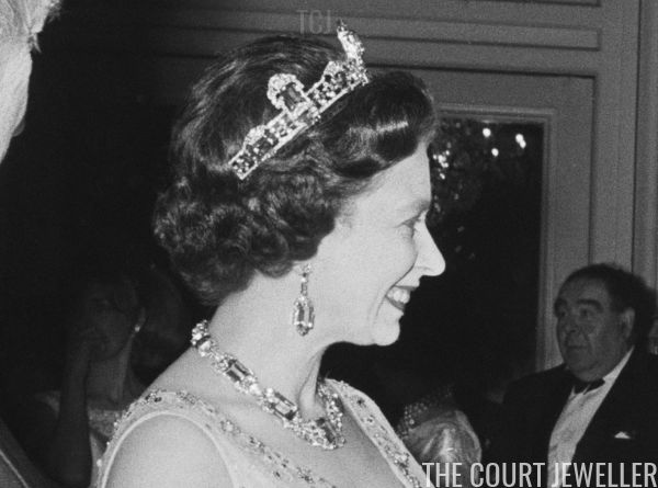 an old black and white photo of two women in tiaras talking to each other