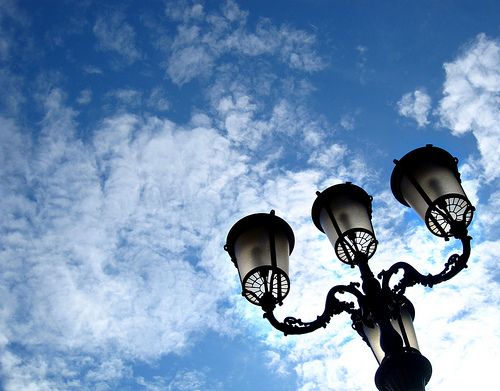 three street lamps against a blue sky with clouds