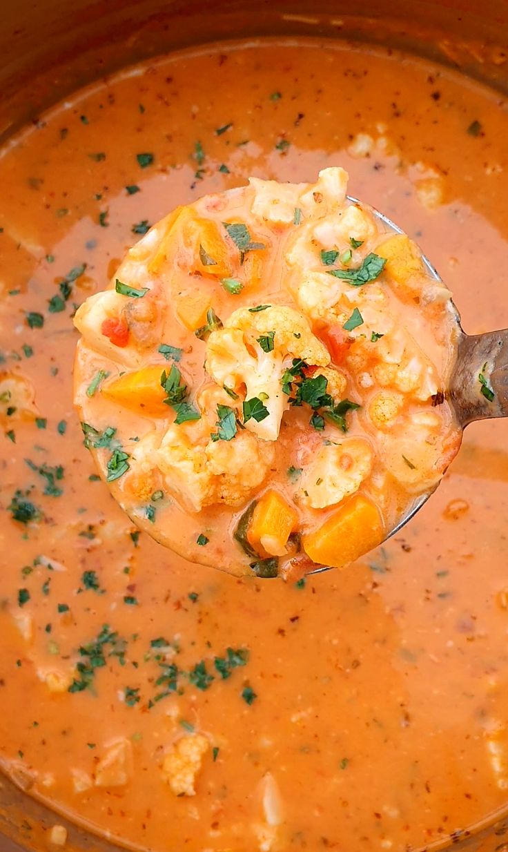 a ladle full of soup is being held by a spoon