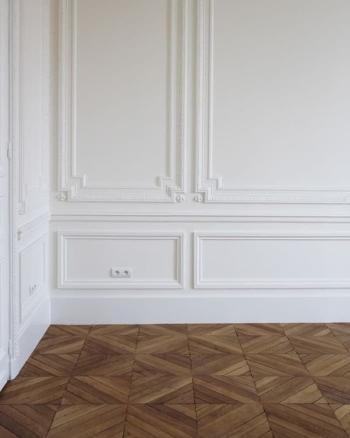 an empty room with wood flooring and white wall paneling on the walls is shown