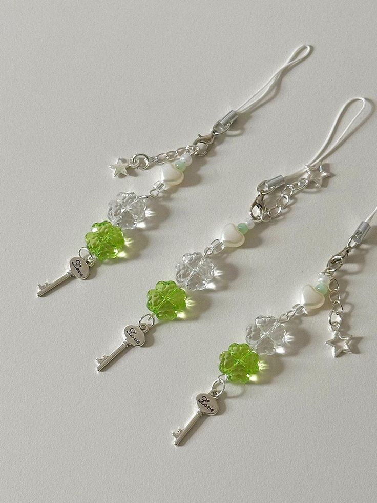 three pairs of earrings with green and white beads on the earwires, hanging from silver hooks