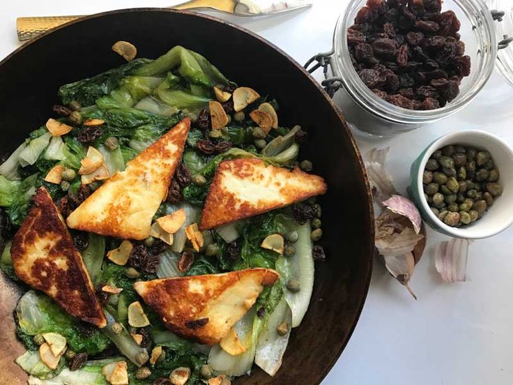 a pan filled with food sitting on top of a table next to bowls of beans