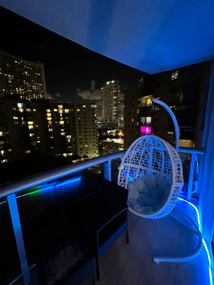 a chair that is sitting on top of a roof in the dark with city lights behind it