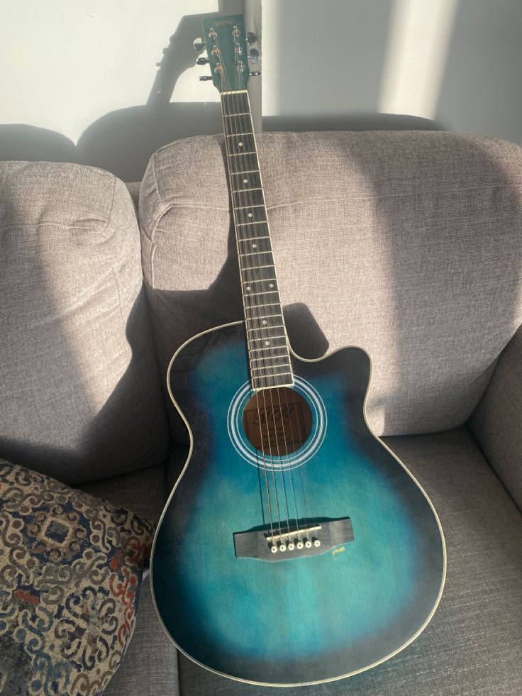 a blue guitar sitting on top of a couch