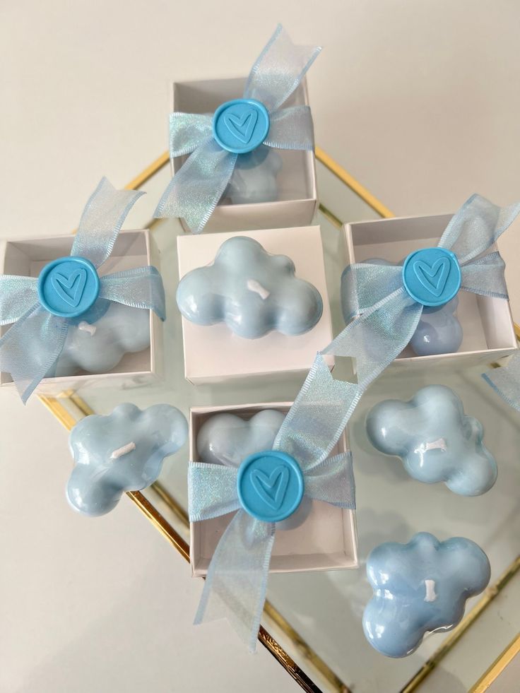 blue and white baby shower items in small boxes on a glass tray with ribbon around them