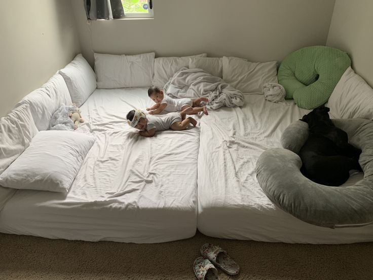 a little boy laying on top of a bed next to a black dog and cat