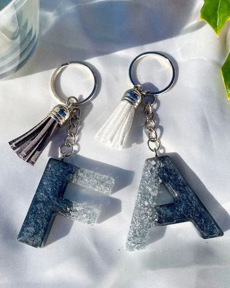 two key chains with letters and tassels on them