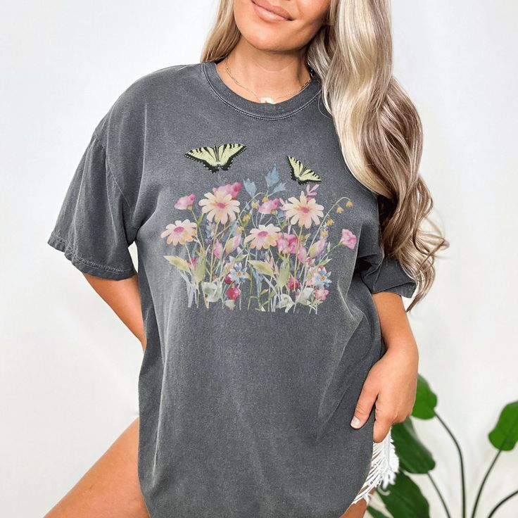 Introducing our lovely boho pastel wild flower t-shirt featuring delicate butterflies fluttering among beautiful blooms. This charming and dreamy piece is perfect for adding a touch of whimsical romance to your wardrobe. Made from soft and comfortable material, this t-shirt will easily become a staple in your closet. Whether you're out exploring nature or simply enjoying a peaceful day out, this top will effortlessly elevate your style with its enchanting design. Embrace the beauty of the outdoo Feminine Relaxed Fit T-shirt For Spring, Cute Butterfly Print T-shirt For Spring, Casual Pink Tops With Floral Patchwork, Feminine Short Sleeve Tops For Garden Party, Cute Butterfly Print Summer T-shirt, Cute Butterfly Print T-shirt For Summer, Cute Summer T-shirt With Butterfly Print, Cute Cotton Tops For Garden Party, Cottagecore Floral Print Top For Garden Party