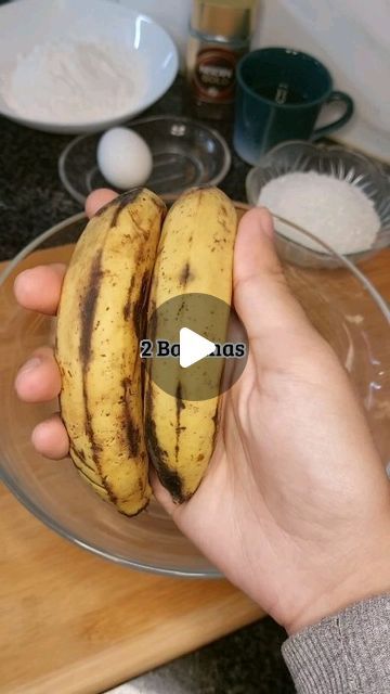 a person holding up two bananas on a glass plate