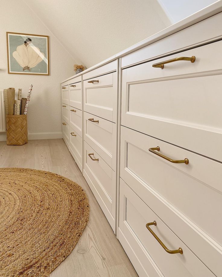 a bedroom with white drawers and gold handles on the dressers in front of it