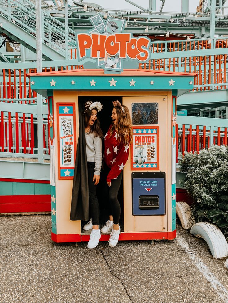 two girls standing in a booth at an amusement park