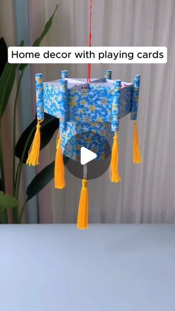 a blue and yellow wind chime with tassels hanging from it's side