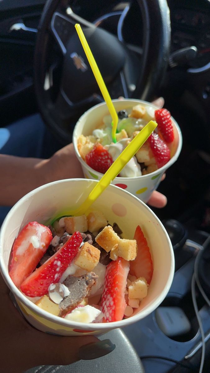 two cups filled with fruit sitting on top of a car dashboard